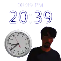 a man is standing next to a clock that says 20:39