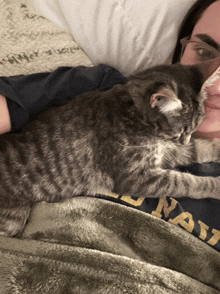 a person laying on a bed with a cat and a shirt that says ' national ' on it