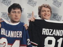 two men holding up jerseys one of which says rozano on it