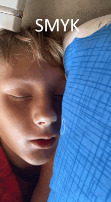 a young boy sleeping on a blue pillow with the word smyk written above him