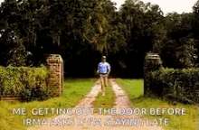 a man is walking down a dirt road in front of a gate with a quote from the movie forrest gump .