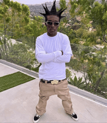 a man with a mohawk and sunglasses is standing on a balcony