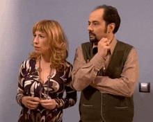 a man and a woman are standing next to each other and the woman is wearing a dress with the letter b on it