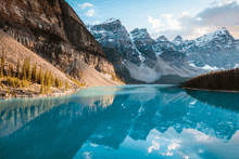 a lake surrounded by mountains and trees with mountains reflected in the water