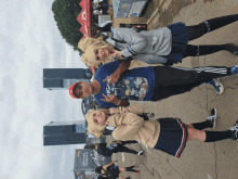 a man in a blue shirt with the letter x on it poses with two girls