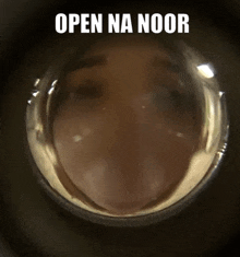 a close up of a person 's face through a door peephole with the words `` open na noor '' written above it .