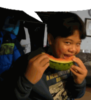 a young boy eating a slice of watermelon wearing a shirt that says a new twenty racing