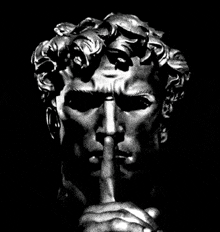 a black and white photo of a statue with a finger on his mouth