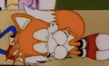 a close up of a cartoon character laying on the ground covering his face .