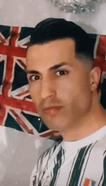 a man is standing in front of a british flag and making a funny face .