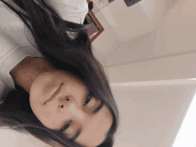 a woman with long black hair is laying down and smiling for the camera