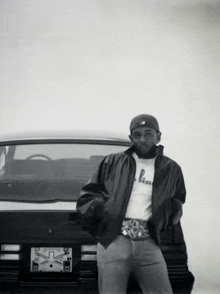 a black and white photo of a man standing in front of a car with a license plate that says x