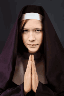 a woman in a nun 's veil is praying with her hands folded