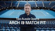 a man stands in front of an empty tennis court with the words two aussie opens arch is match fit