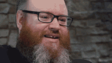 a man with glasses and a beard is smiling with his mouth open