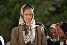 a woman wearing a scarf on her head stands in a crowd of people