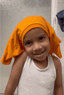 a little boy wearing a white tank top and an orange headband