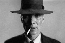 a man in a fedora smoking a cigarette