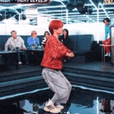 a man with red hair is dancing on a stage in front of a group of people .