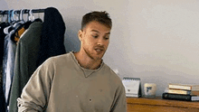 a man with a beard is standing in front of a dresser in a bedroom .