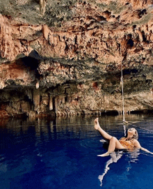 a woman is floating on a rope in a cave in the water