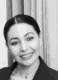 a black and white photo of a smiling woman in a suit .