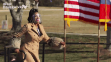 a woman wearing a face shield stands in front of american flags with the words real housewives out of context on the bottom