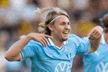 a soccer player wearing a blue shirt with a vw logo on it is celebrating a goal .