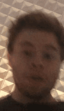 a blurry picture of a man 's face with a geometric pattern in the background