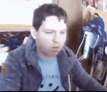 a man wearing a blue shirt and a gray jacket is sitting in front of a computer .