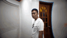 a man in a white shirt is standing in front of a door .