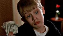 a young boy is holding a bunch of money in his hands .