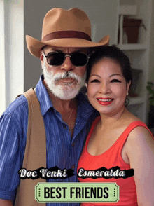 a man in a cowboy hat and sunglasses stands next to a woman in a red tank top