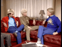 a group of people are sitting on a couch and one of them is wearing a blue sweater that says ' time '