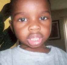 a close up of a child 's face with a plant behind him