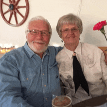 a man and woman posing for a picture with a wagon wheel behind them