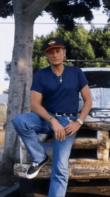 a man wearing a harley davidson hat is sitting on the hood of a car