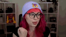 a woman with pink hair is wearing a purple beanie with a teddy bear on it