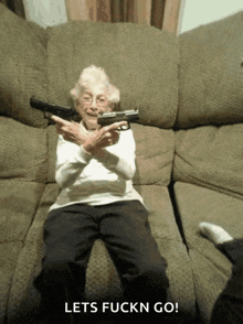 an elderly woman is sitting on a couch holding a gun with the words lets fuckn go below her