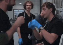 a man wearing blue gloves and a watch talks to another man