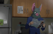 a man wearing a bat mask reads a magazine in front of a sign that says please clean