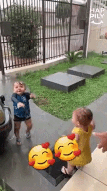 a boy and a girl are standing next to each other in front of a fence in the rain .