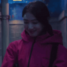 a woman in a pink jacket is smiling and looking to the side