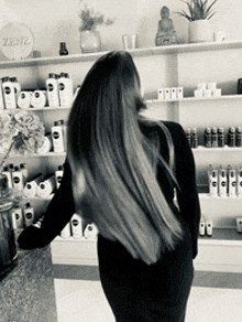 a woman in a black dress is standing in front of a shelf with zenz written on it