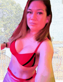 a woman in a red bikini is standing in front of a fence