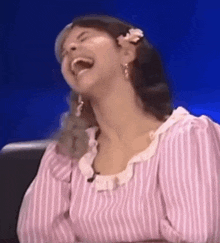 a woman in a pink and white striped dress is laughing with her mouth open .