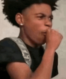 a young man with a backpack is covering his mouth with his hand and making a funny face .