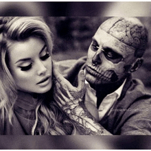 a man with a skull tattoo on his face is touching a woman 's face in a black and white photo