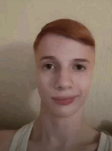 a young man with red hair is smiling and looking at the camera .