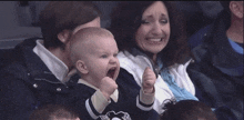 a baby in a pittsburgh penguins shirt holds up his fist